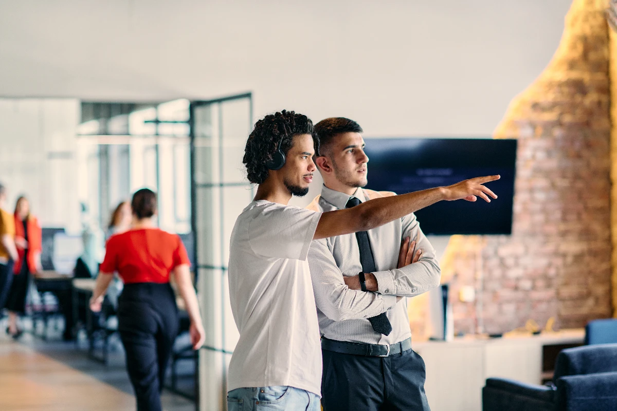 Two men in a coworking space, one pointing