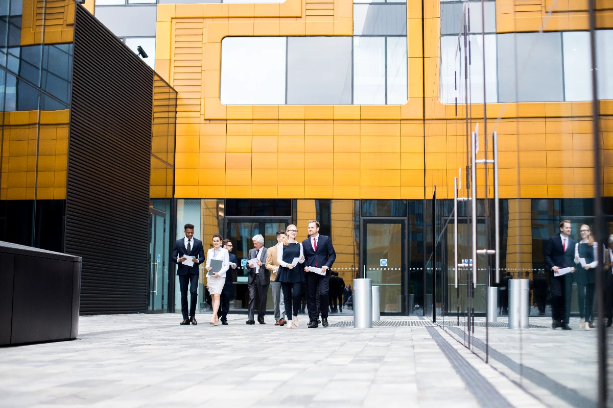 Office workers exiting building, discussing how to choose a business location