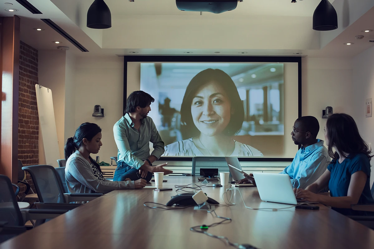 A team holding a hybrid meeting, making use of room equipment like the projector