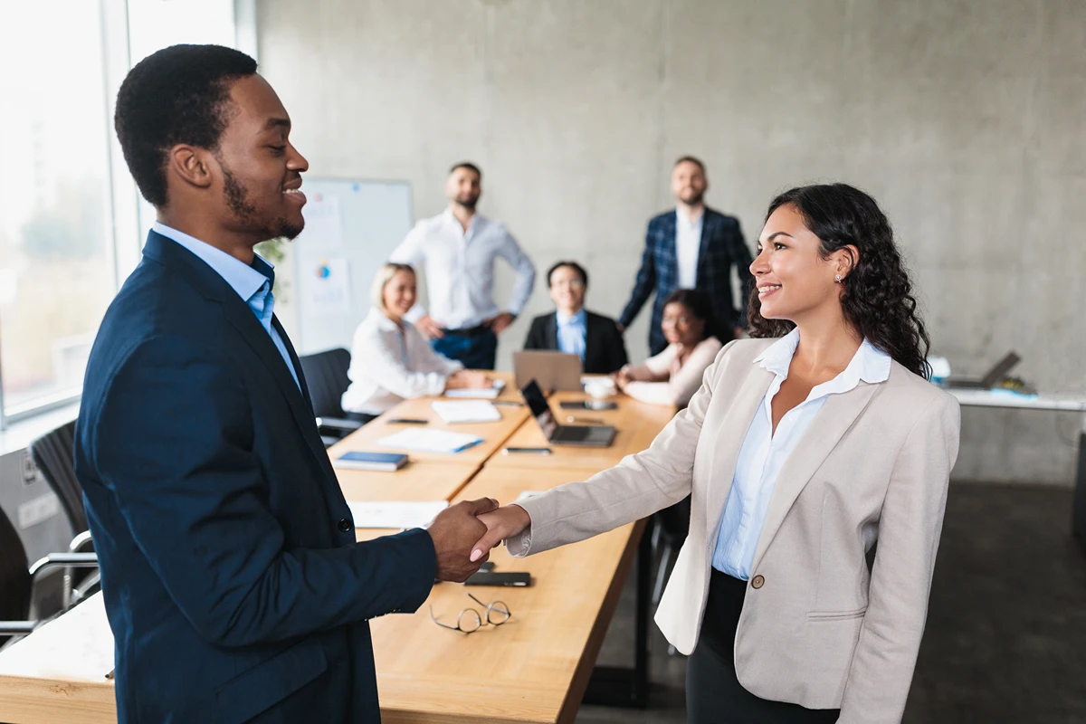 Businesspeople exhibiting good business meeting etiquette, shaking hands with a smile